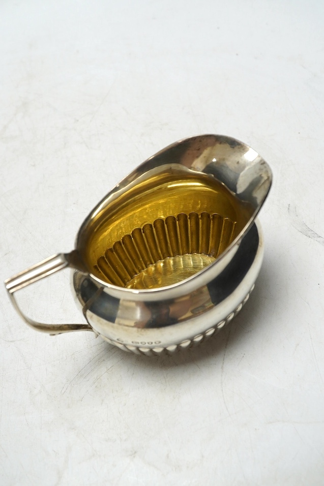 A matched late 19th/early 20th century demi-fluted silver three piece tea set, London, 1884 and later, gross weight 15.5oz. Condition - poor to fair